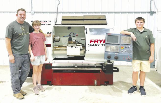 Heinrich Muller (left) with his children, Cecilia (middle) and Conrad (right) with some of the machinery in the new KOTA shop.