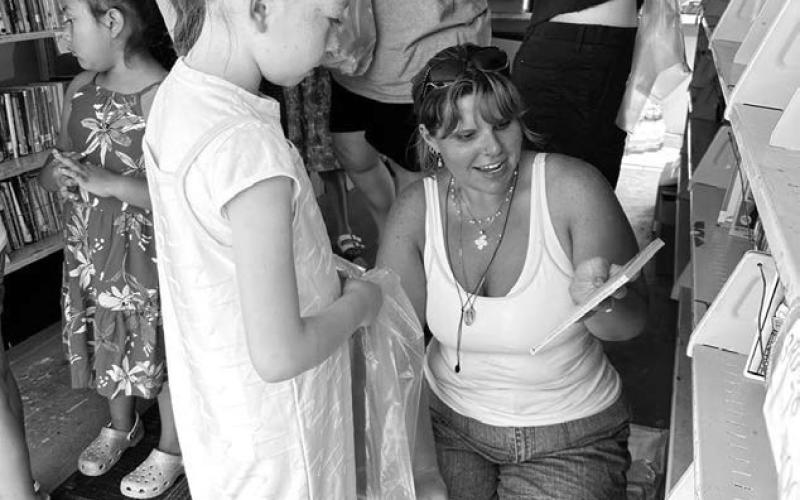 A volunteer with the St. Joseph’s Indian School Bookmobile helps Bexley Dupris select a book during the bookmobile’s annual stop in Timber Lake last Wednesday, June 18. Visitors of all ages were invited to enjoy snacks and choose free books. Photo by Kathy Nelson