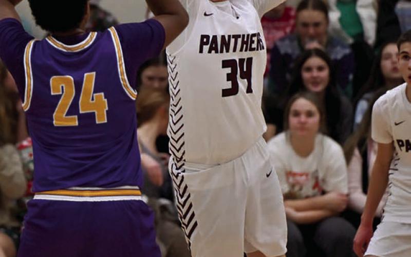 Rance Martin(34), a junior forward for Timber Lake, gets in the face of a shooter during boys baskeball action before the holiday break. The Panthers, 1-2, will play four games over the next week. Photo by Marie Du Preez