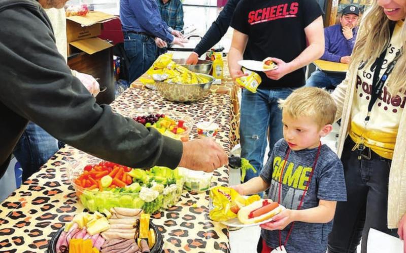 Volunteers from the Timber Lake Rodeo Association served a hot dog supper. Here Richard Gross helps Barrett Hermes to some veggies.