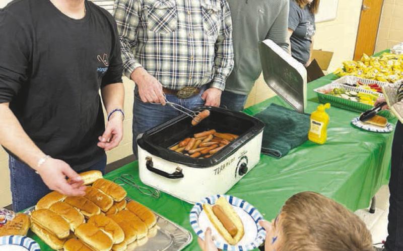 Timber Lake Rodeo Association officers serve supper to Maverick Linderman. L-R are Shaun Maher, Rusty Gebhardt, Brent Schweitzer, and teacher Cara Lei.