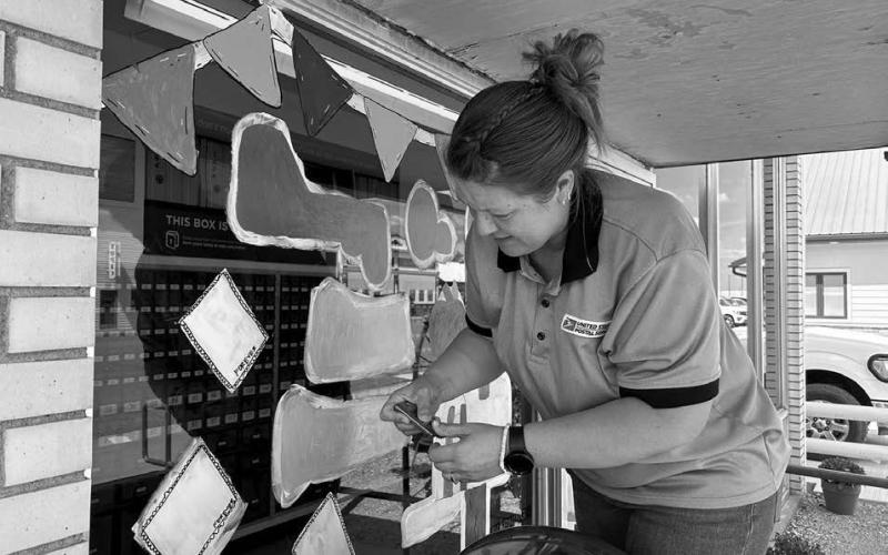 Timber Lake Post Office employee Amy Bridges paints the front window of the Post Office with a welcome back to school for students. The 2025-26 school year got underway Monday, Aug. 18. Photo by Jon Flatland