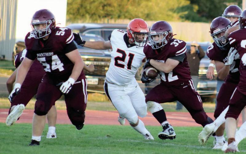 Timber Lake senior running back Gabe Keller (32) blasts through a hole in the Philip defensive line as he follows the blocking of teammate Mason Bickel (54) during first half action of the Panthers 29-6 loss to the Scotties last Thursday, Aug. 29, at Kraft Field. Pursuing Keller for Philip is defensive tackle Evan Kroetch (21). Photo by Jon Flatland