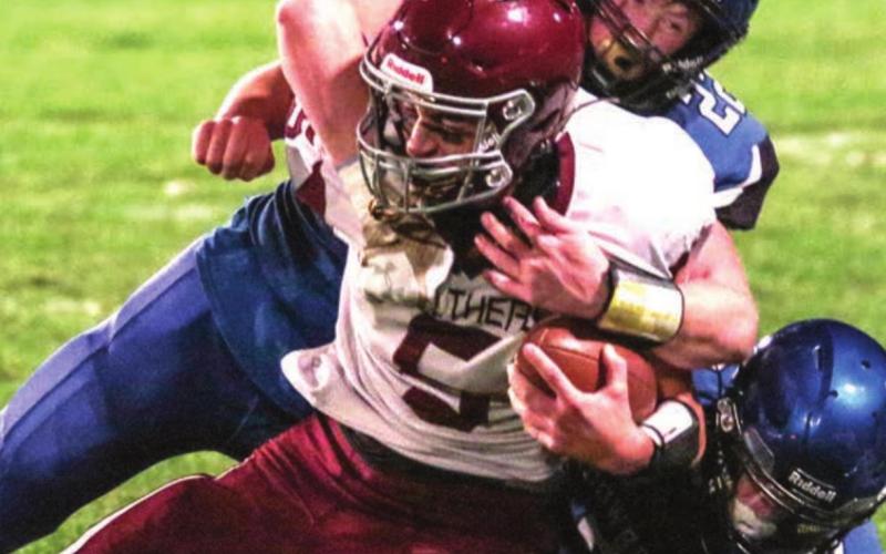 Lemmon/McIntosh’s Tell Mollman (22) and Riley Tennant (7) bring down Timber Lake’s Trenton Hansen during their game in Lemmon on Friday. Photo by Jon Flatland
