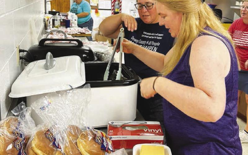 LEFT: 4-H moms Denise Perryman and Mitzi Simon serve hot dogs and burgers from the kitchen. Kyle Nilson grilled outdoors.