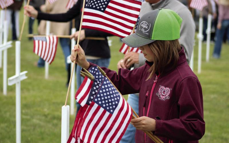 Julia Ingles of Lemmon, the granddaughter of Johnny Dean and Ina Boldt of Isabel, was among those who placed flags on a field of crosses while the names of local veterans who have passed was read during the Isabel American Legion Smith-Wright Post 120 and Auxiliary program at Hillview Cemetery on Monday, May 26. Photo by Jon Flatland
