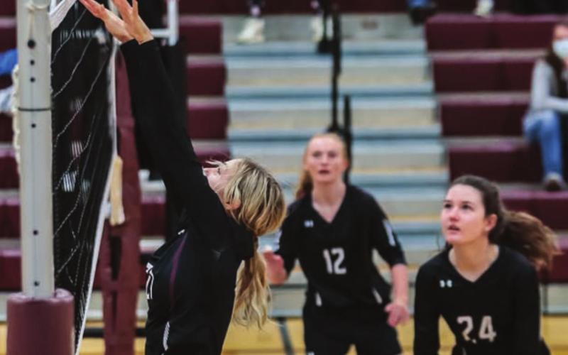 Harlee Hulm pushes the ball over the net as Jordan Jones (12) and Sara Holzer (24) watch during a JV match versus Bennett County.