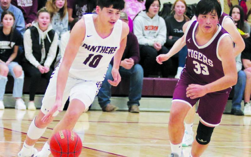 Junior guard Elijah Brewer (10) pushes the ball up-court on a fast-break while McIntosh sophomore Desmond Steele (33) looks for defensive help during Timber Lake’s win over the Tigers in Little Moreau Conference boys basketball action on Monday, Jan. 9. Photo by Jon Flatland