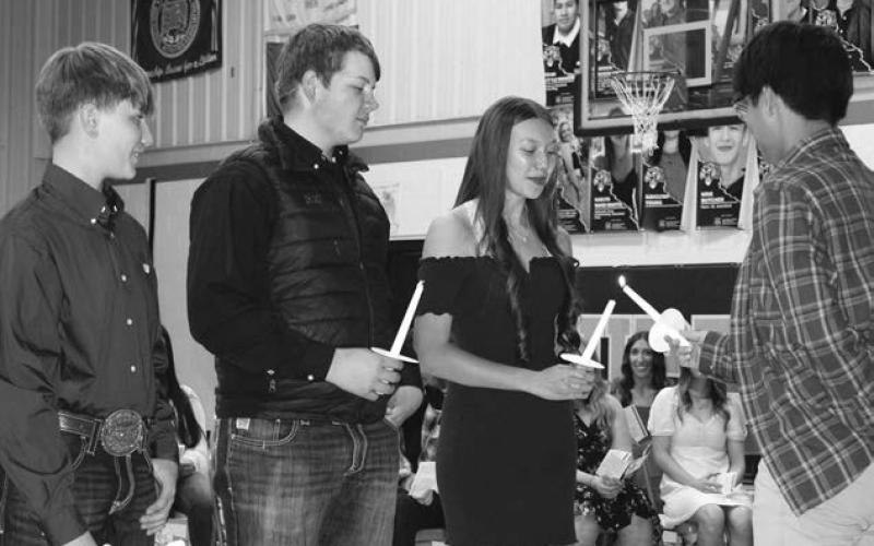 National Honor Society member Kayle Bridwell lights the candles of (L-R) Hudson Terveen Smith, Tanner Thorstenson, and Samara Ward Martel as they joined the Dupree NHS.