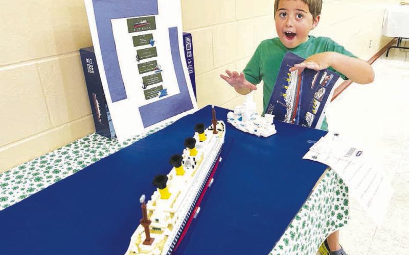 Austin Lindskov (right) and other 4-H youth showed their livestock at the Dewey County Fair on July 24. Robin Hanssen (left) interviewed the 4-Hers about their animals. Dad Bryce Lindskov is in back. Milo Linderman displayed his replica of the Titanic, made from Legos.