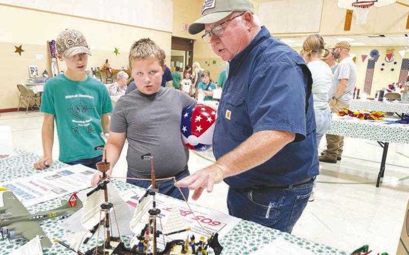 Roger Lawien offers some praise and suggestions for Hank Anderson on the sailing ship he built from Legos as brother Gus (left) looks on.