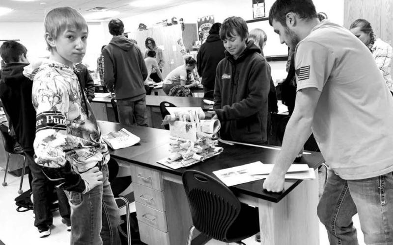 Jayce Lawrence, a senior, instructs Isaac Assman (LEFT) and Jaxon Wiedmer, eighth graders, on engineering techniques. The high school students will present three more lessons to grades 3-8 in February and March.
