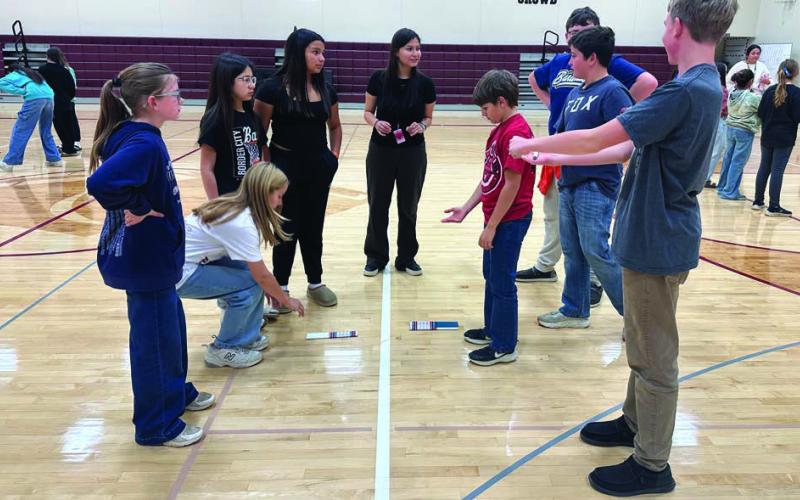 Middle school students played hand games. L-R are Stella Nilson, Sophia Gross, Leah Eigelaar, Marley Ward, Hocokanwin (Cho) Chasing Hawk (instructor), Kayne Palmer, Luke Biegler, Barrett Maciejewski, and Maddoc Boysen.