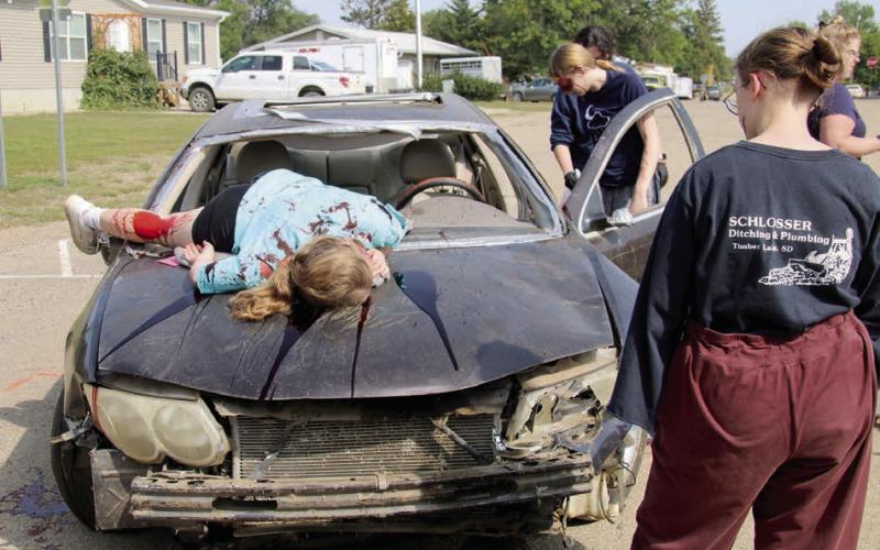 Injured passengers are helped from the back seat while a crash victim lies on the hood of a car involved in an automobile accident caused by texting. This was a scene at a mock two-vehicle collision that was part of Freshman Impact: Caught in the Moment, a prevention program aimed at teenagers. Photo by Roger Lawien