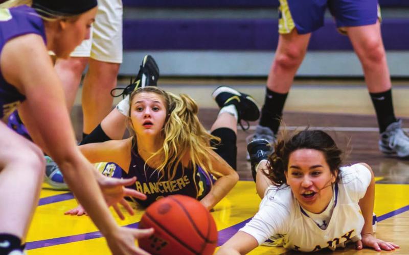 Harding County’s Bailey Verhulst (LEFT) scoops up the basketball after Dupree’s RaeLynn Vines (RIGHT) dove to keep it away from Rancher Reese Hunsucker (CENTER) during the Little Moreau Conference game.