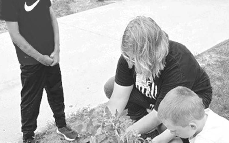 RIGHT (l-r): Bryson Long waits patiently for his turn as Megan Zeug (a parent volunteer) helps Trevor Aberle plant his tomato plant.