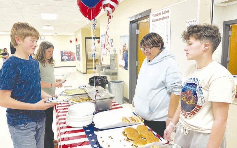 Nevaeh Fernandez and Claire O’Leary of the TLHS Native American Club serve up supper for Max and Naomi Goldade at the America 250-themed Family Night at Timber Lake School on March 24.