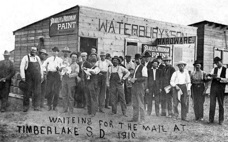 Before Timber Lake had a post office, mail was distributed at the First State Bank and Waterbury Hardware. A young Wenzel Leff is pictured (left of center), reading a letter.