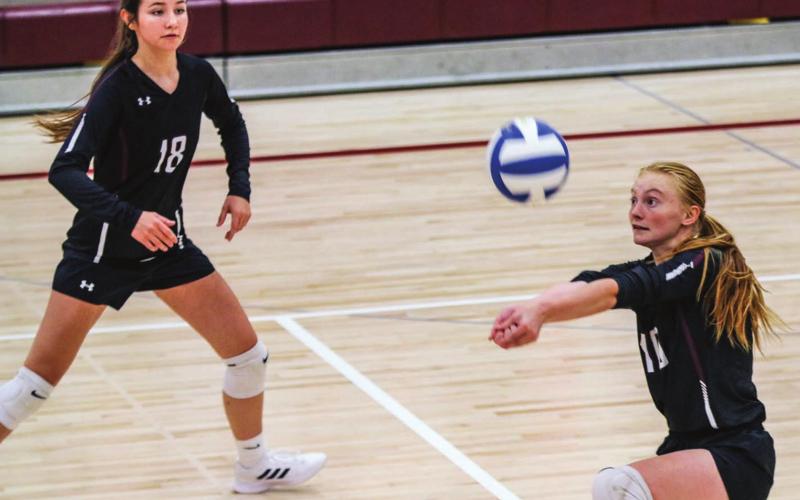 Jordan Jones prepares to return a serve while teammate Natalie Gross watches during recent volleyball action. File photo by Jon Flatland