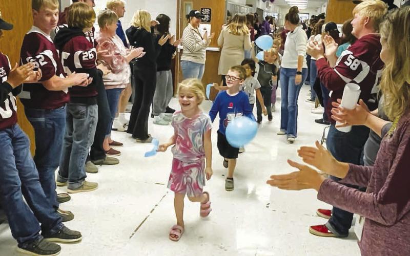Photo by Kathy Nelson Timber Lake Elementary students and staff, waving blue ribbons and balloons, paraded through the hallways on Monday as high school and middle school students and staff cheered for them in celebration of their recognition as a National Blue Ribbon School. Here Rose Maher and Lincoln Aberle lead the parade.