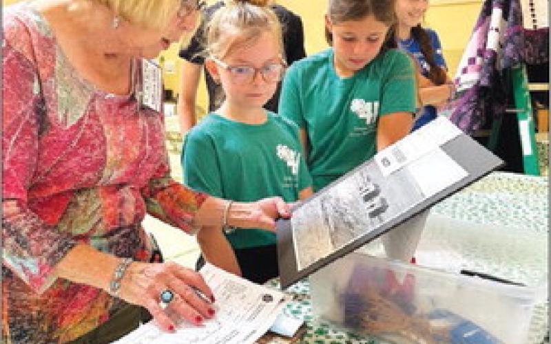 Judge Adele Enright looks at photography entries with Stella Nilson and Finley Boldt at the Dewey County 4-H Achievement Day on July 27.