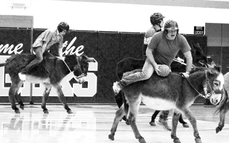 Players in the Donkey Basketball game sponsored by the Dupree Booster Club last Thursday, Jan. 23, had a hard time figuring out how to steer their donkeys ... and spent more time concentrating on staying on-board than they did scoring a basket. Above, Tee Birkeland, left, tries to get his donkey moving while Terry Russell (with basketball) wonders if he can stay on long enough to get a shot. Behind Russell is Kaden Deal. Photo by Patty Peacock