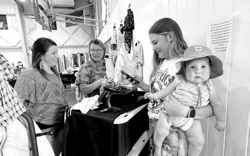 Kenna Webb (right) holds Aria Dupris while baby’s mom, Kathryn (left), does some shopping, and Kenna’s mom, Sue Kvarness of Selby, helps with the sale. Photos by Kathy Nelson