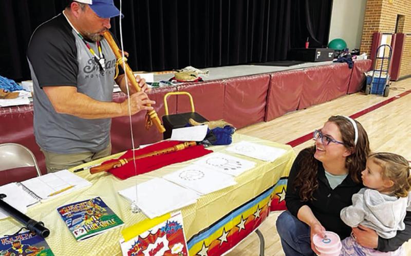Mark Mindt (LEFT), creator of Koda the Warrior, a Native American superhero, plays the flute for Shanna Martin and her daughter, Crozbee, at the Timber Lake Elementary School Family Fun Night on March 23. Mindt visited elementary classes throughout the day prior to taking part in the Family Fun Night. (More on page 16) Photo by Kathy Nelson