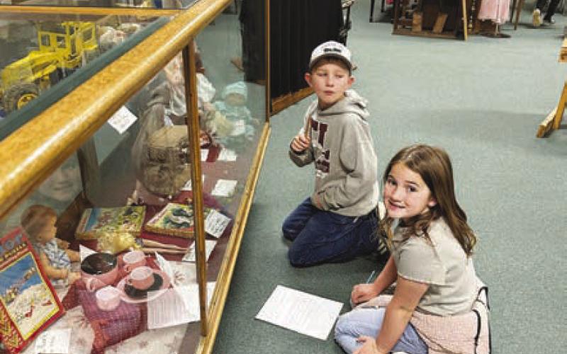 Shane Locken and Baicyn Lei check out the toy exhibit looking for the answer to a questions on the scavenger hunt at the Timber Lake Museum.