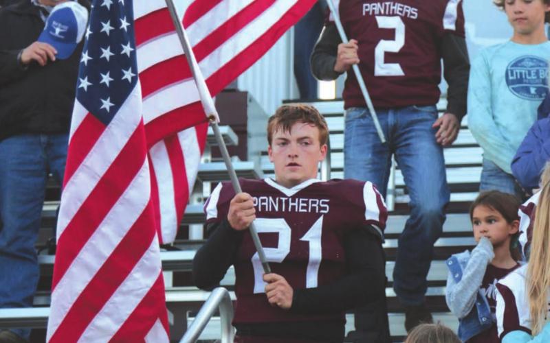 Timber Lake seniors Caleb Quinn (21) and Brandt Ducheneaux (2) carry American flags from the crow’s nest and through the stands prior to the start of the Panthers’ football game with Harding County/Bison last Friday. All the senior players carried flags to the field for the National Anthem.