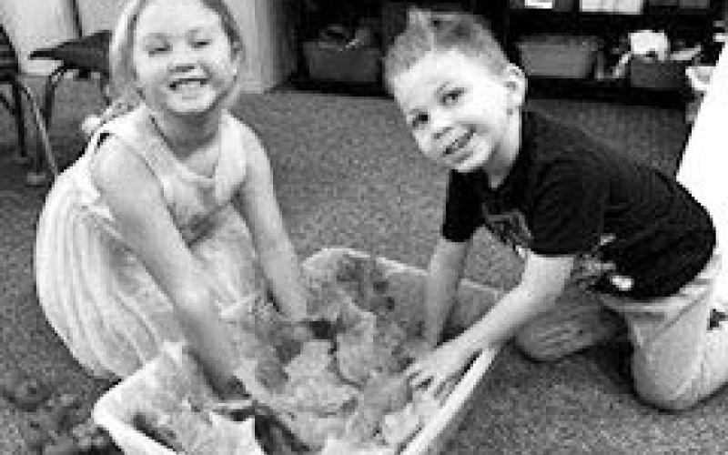 Lyllian Tesch and Layson Gimbel are digging through leaves looking for pumpkins and apples.