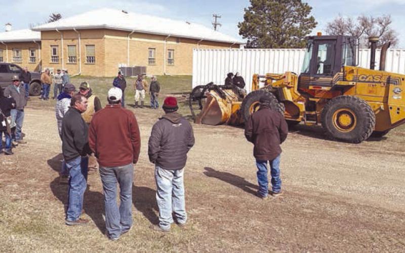Bidders and onlookers lined up for auction of the surplus 1997 Case loader from the Dewey County Highway Department on April 8. Rod Enright conducted the auction, which brought $59,000 from Dan Molitor of Morristown. Photo by Kathy Nelson