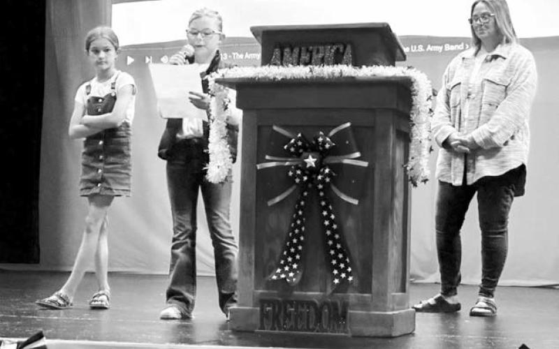 At the Timber Lake Memorial Day program, students Ada OLeary (LEFT) and Stella Nilson read their winning entries in the Americanism essay and poetry contests. Jae White (RIGHT) of the Timber Lake American Legion Auxiliary Unit 83 was emcee. Dewey County Sheriff Ash Arpan was the guest speaker. Photo by Kathy Nelson