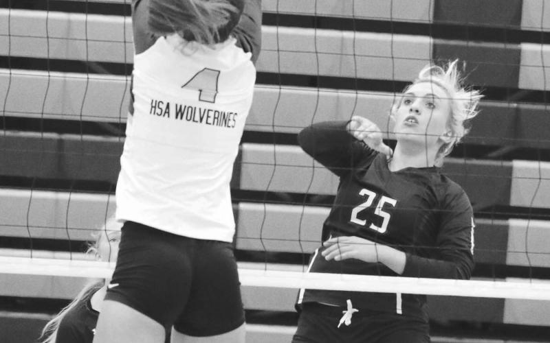 Sophomore outside hitter McKenzi Vomacka (25) puts a shot over the outstretched hands of an unidentified Herreid-Selby defender (4) during recent action. Photo by Jon Flatland