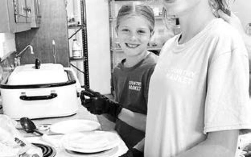 Days of 1910 kitchen helpers Raelyn Quaschnick of Mobridge and Taylor McComsey of Aberdeen learned all about volunteering from their grandparents, John and Patty Linderman.