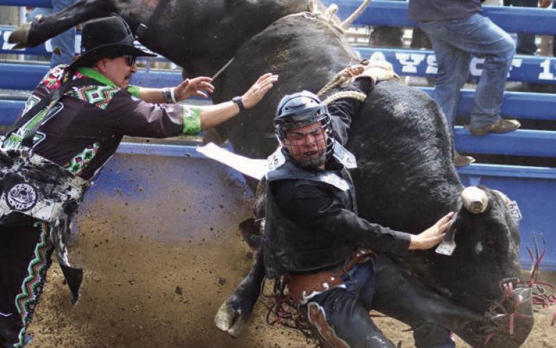 Faith bull rider Roy Antrim found himself someplace a bull rider never wants to be - hung up and in the well - at the Timber Lake High School Rodeo last Saturday, May 25. Bull fighter Layton Woodbury (left) moves in to try and free Antrim, who eventually escaped bruised but otherwise uninjured. Photo by Jon Flatland