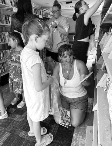 A volunteer with the St. Joseph’s Indian School Bookmobile helps Bexley Dupris select a book during the bookmobile’s annual stop in Timber Lake last Wednesday, June 18. Visitors of all ages were invited to enjoy snacks and choose free books. Photo by Kathy Nelson