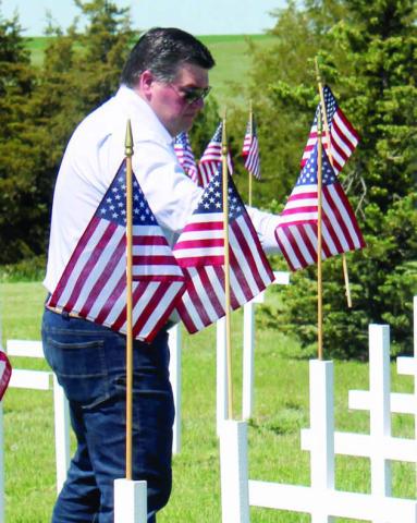 Ryan Maher places a flag on a cross marking a grave during the Memorial Day Program at Hillview Cemetery in Isabel. The placing of the flags is a tradition during the program. Photo by Patty Peacock.