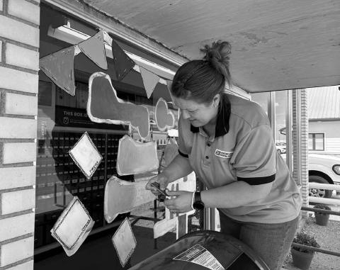 Timber Lake Post Office employee Amy Bridges paints the front window of the Post Office with a welcome back to school for students. The 2025-26 school year got underway Monday, Aug. 18. Photo by Jon Flatland