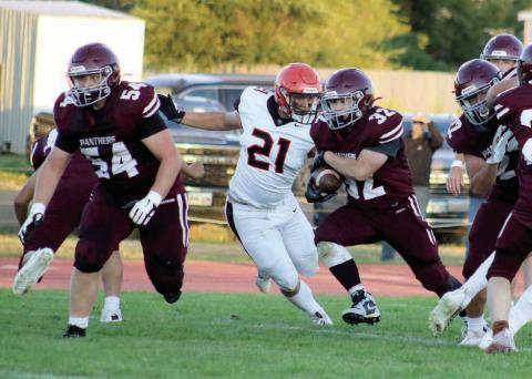 Timber Lake senior running back Gabe Keller (32) blasts through a hole in the Philip defensive line as he follows the blocking of teammate Mason Bickel (54) during first half action of the Panthers 29-6 loss to the Scotties last Thursday, Aug. 29, at Kraft Field. Pursuing Keller for Philip is defensive tackle Evan Kroetch (21). Photo by Jon Flatland
