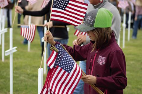 Julia Ingles of Lemmon, the granddaughter of Johnny Dean and Ina Boldt of Isabel, was among those who placed flags on a field of crosses while the names of local veterans who have passed was read during the Isabel American Legion Smith-Wright Post 120 and Auxiliary program at Hillview Cemetery on Monday, May 26. Photo by Jon Flatland