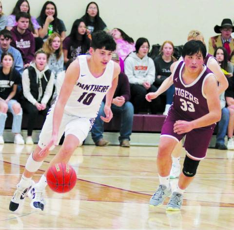 Junior guard Elijah Brewer (10) pushes the ball up-court on a fast-break while McIntosh sophomore Desmond Steele (33) looks for defensive help during Timber Lake’s win over the Tigers in Little Moreau Conference boys basketball action on Monday, Jan. 9. Photo by Jon Flatland