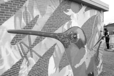 Longtime RedCan artist Cufo works on a hummingbird mural on the Si Tanka Trailer on East Landmark Avenue in Eagle Butte last week during the Cheyenne River Youth Project’s annual RedCan Graffiti Jam. It is one of eight new large-scale murals painted by the nine headlining artists at RedCan. Photo courtesy of Cheyenne River Youth Project