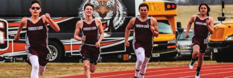 Timber Lake runners (L-R) Aidan Rough Surface, Tell Murray, Jaiden Ducheneaux and Ashton Kerstiens sprint toward the finish line in the 400m run. Photo by Robert Slocum