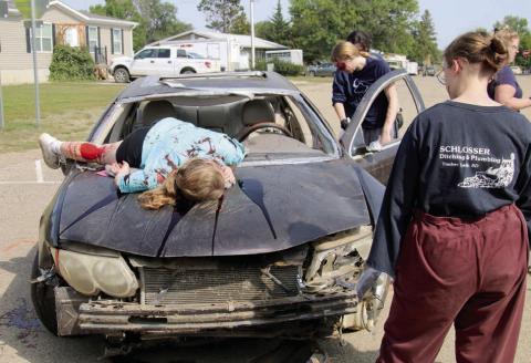 Injured passengers are helped from the back seat while a crash victim lies on the hood of a car involved in an automobile accident caused by texting. This was a scene at a mock two-vehicle collision that was part of Freshman Impact: Caught in the Moment, a prevention program aimed at teenagers. Photo by Roger Lawien