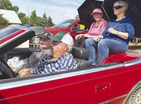 Parade marshals, driven by Marty Biegler in his red convertible, were (front) Rod Enright, his wife Mavis Enright (in blue) and her sister, Frances Marshall (in pink).