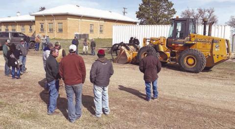 Bidders and onlookers lined up for auction of the surplus 1997 Case loader from the Dewey County Highway Department on April 8. Rod Enright conducted the auction, which brought $59,000 from Dan Molitor of Morristown. Photo by Kathy Nelson