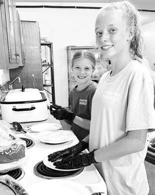 Days of 1910 kitchen helpers Raelyn Quaschnick of Mobridge and Taylor McComsey of Aberdeen learned all about volunteering from their grandparents, John and Patty Linderman.