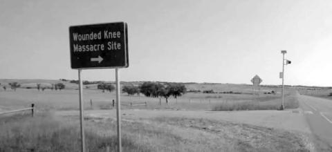 A state tourism sign points travelers in the direction of the Wounded Knee Massacre. South Dakota Searchlight photo by McKenzie Huber