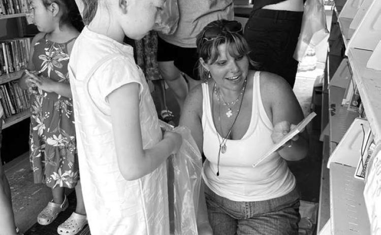 A volunteer with the St. Joseph’s Indian School Bookmobile helps Bexley Dupris select a book during the bookmobile’s annual stop in Timber Lake last Wednesday, June 18. Visitors of all ages were invited to enjoy snacks and choose free books. Photo by Kathy Nelson